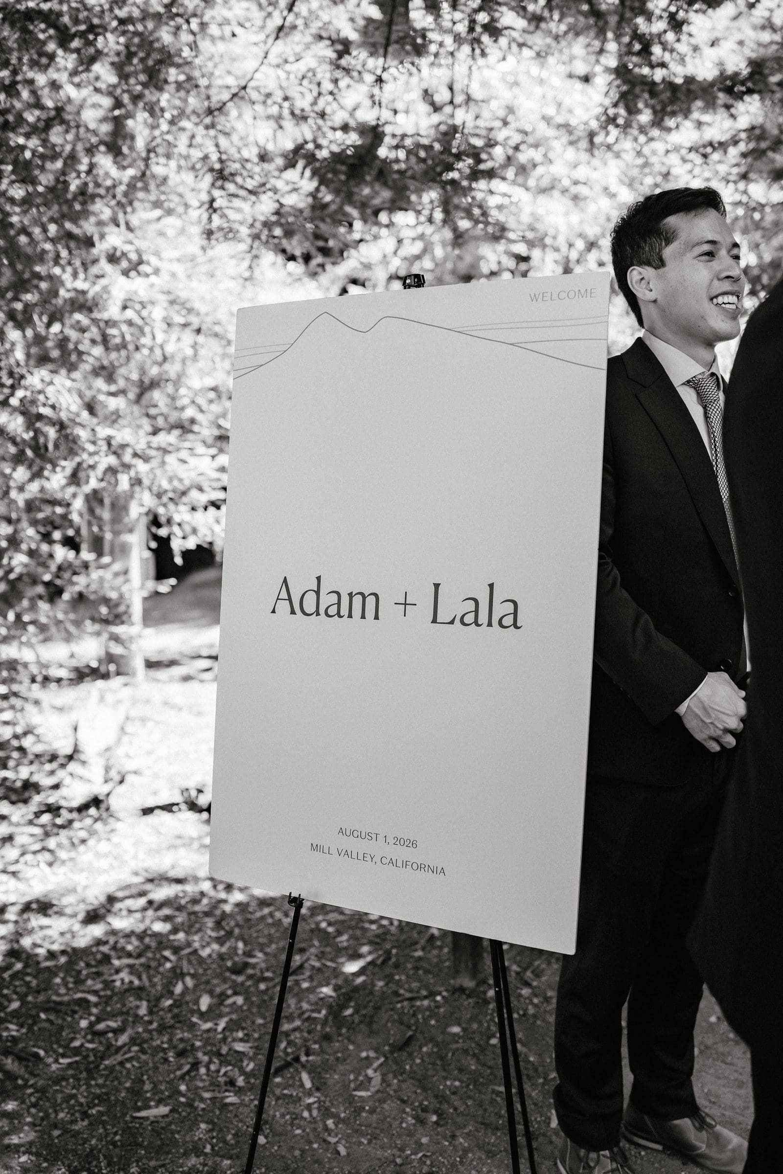 Adam beside the welcome sign, black and white