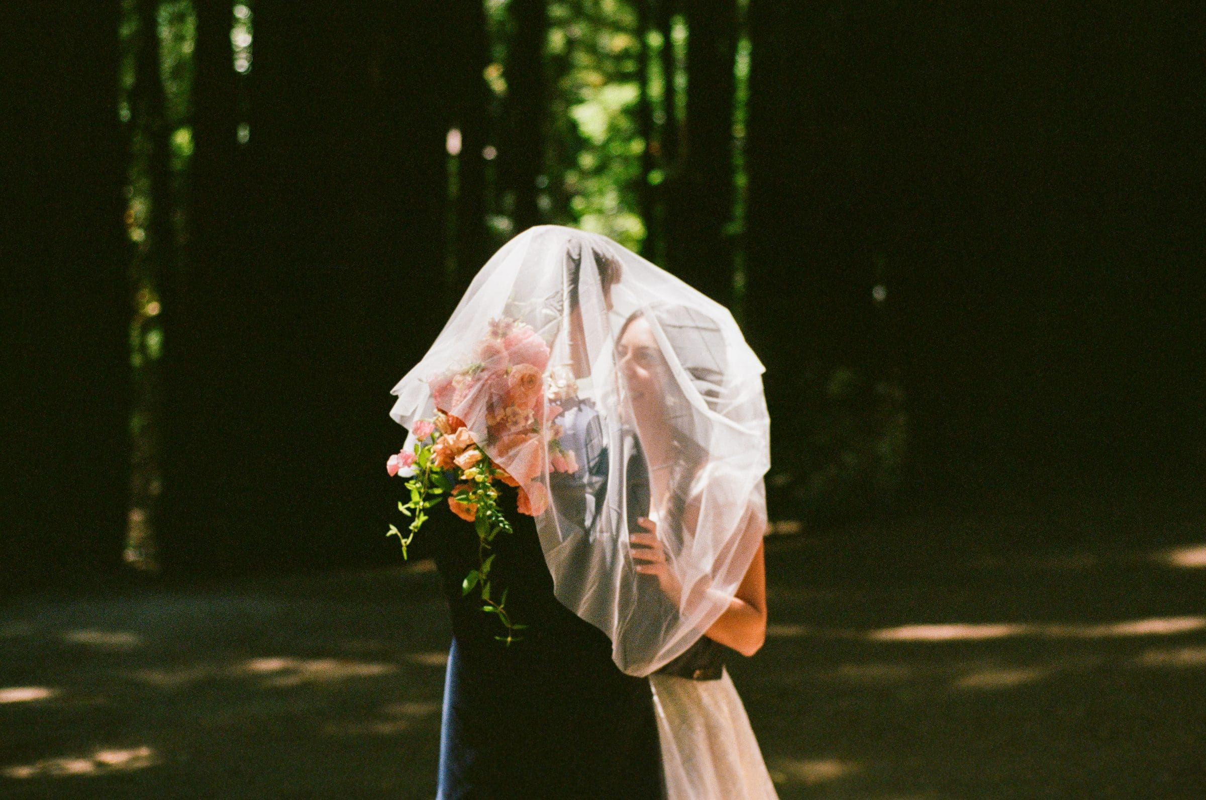 Lala holding her bouquet beneath her veil among the redwoods, on film