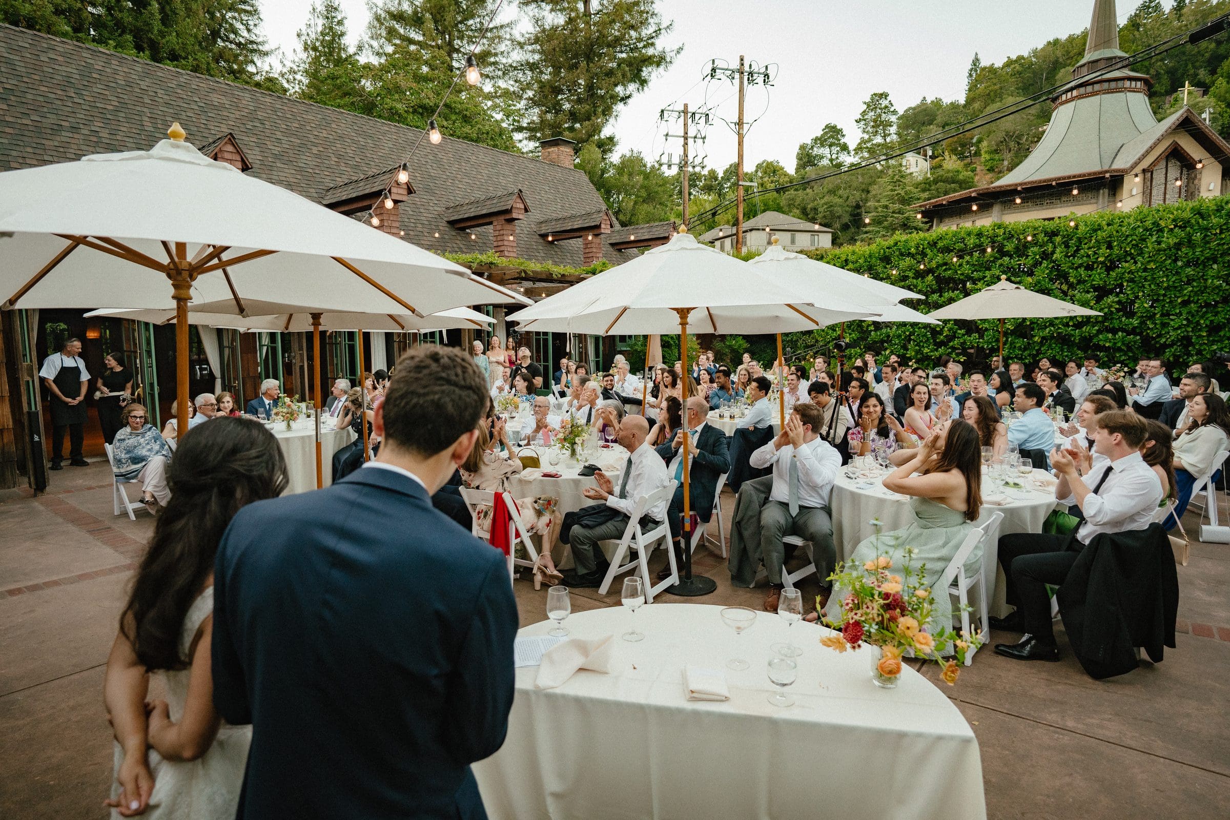 Guests gathered under white umbrellas for a toast at cocktail hour