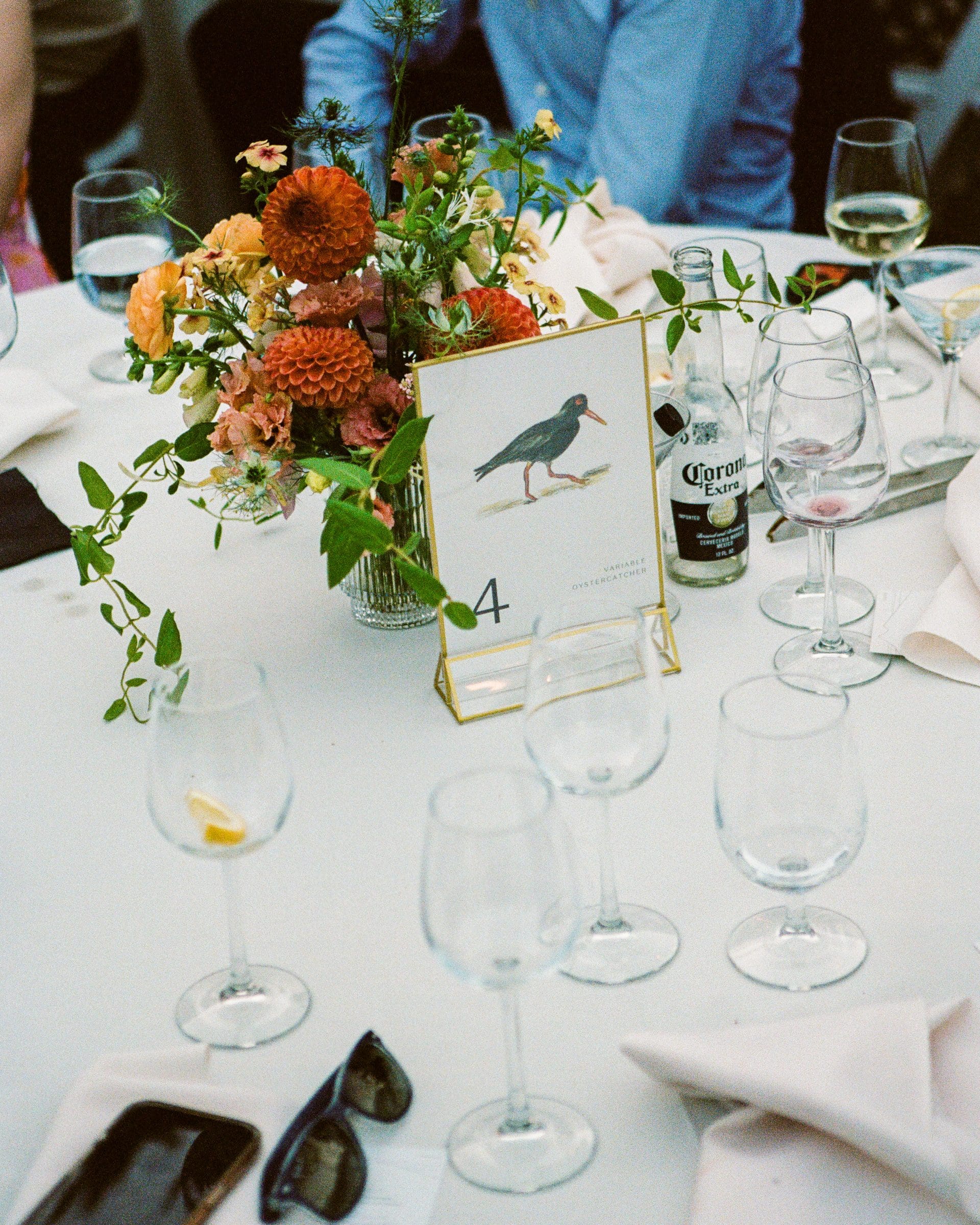 Table setting with orange florals and a table number, on film