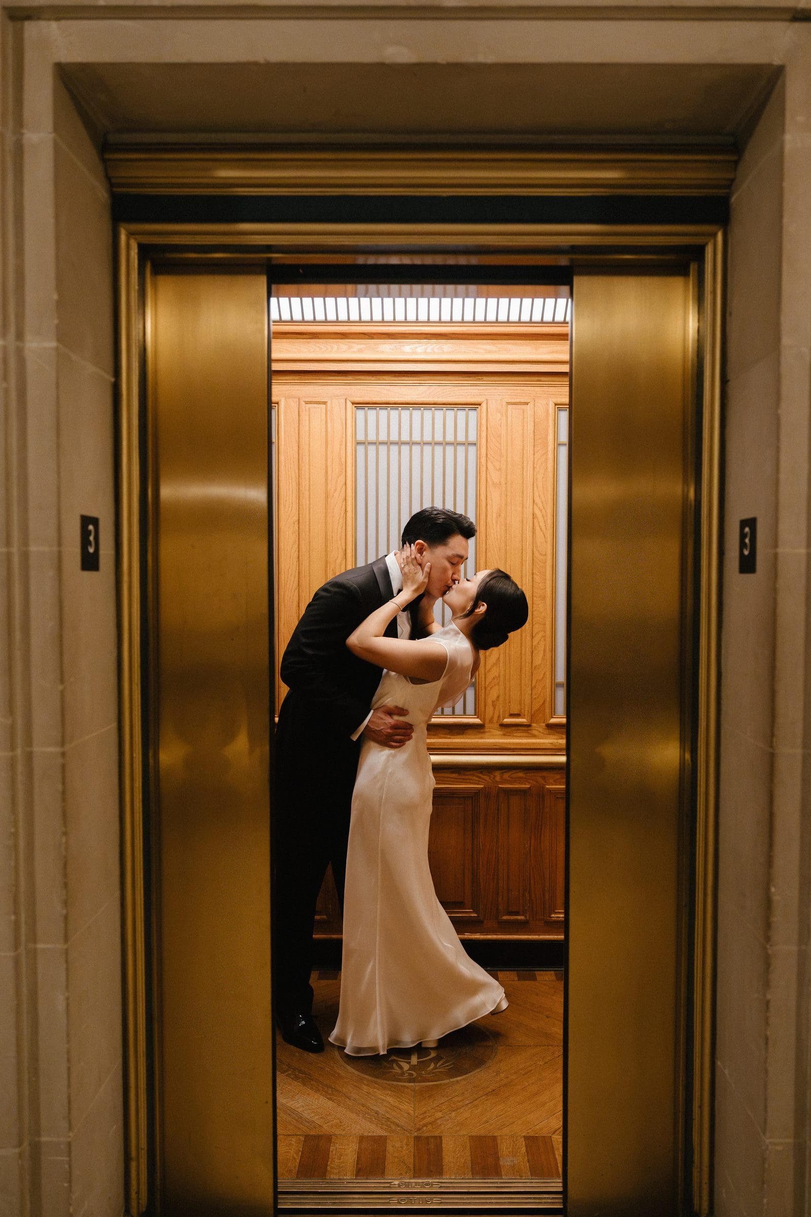 David and Michelle kissing in a gold City Hall elevator
