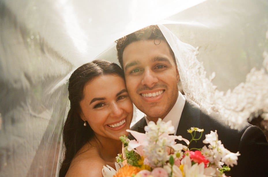 Sofia and Devin smiling under her veil with her bouquet at their wedding at Waterfall Lodge & Retreat