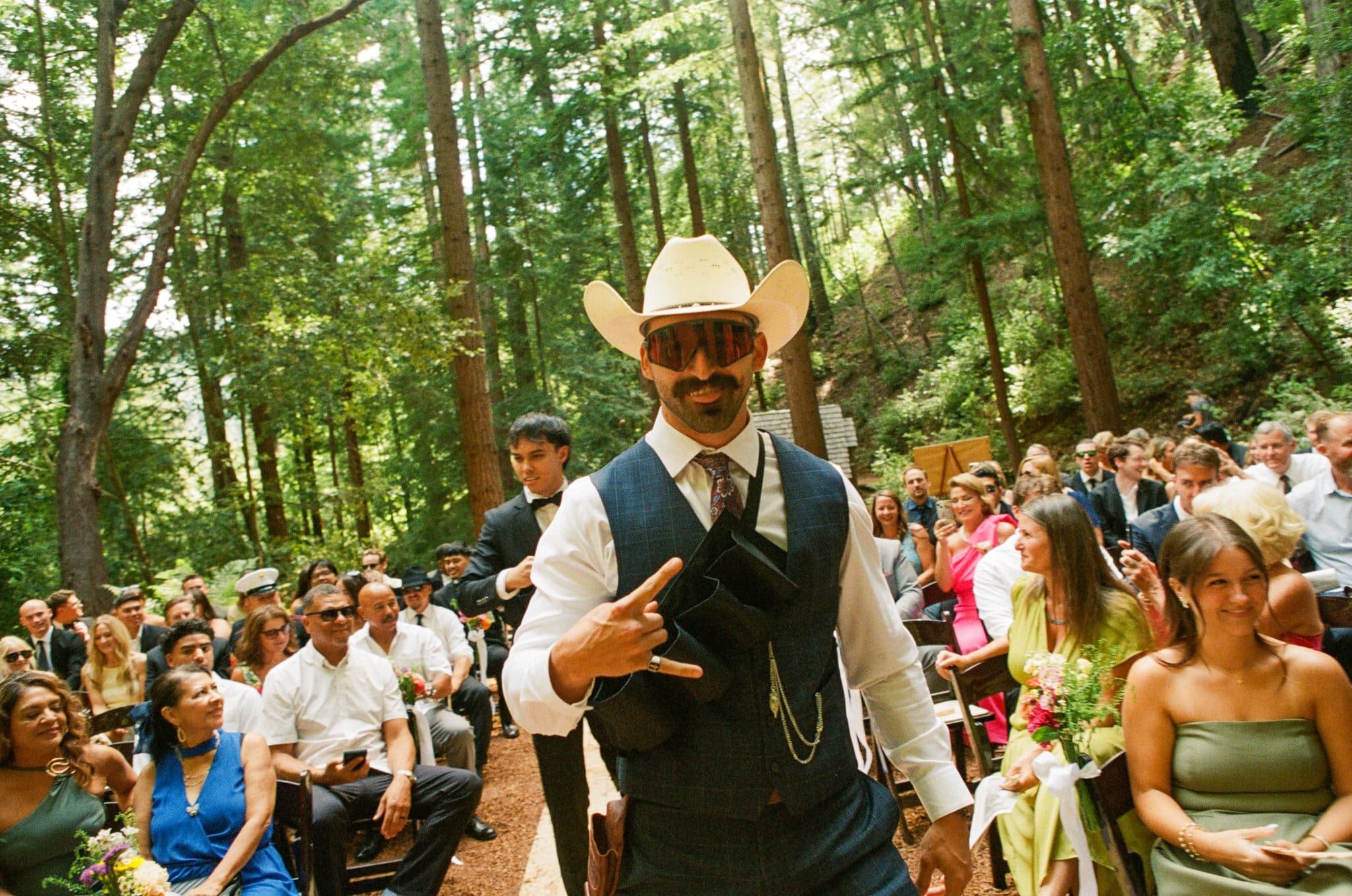 Guest in a cowboy hat greeting the crowd before the redwood ceremony, on film