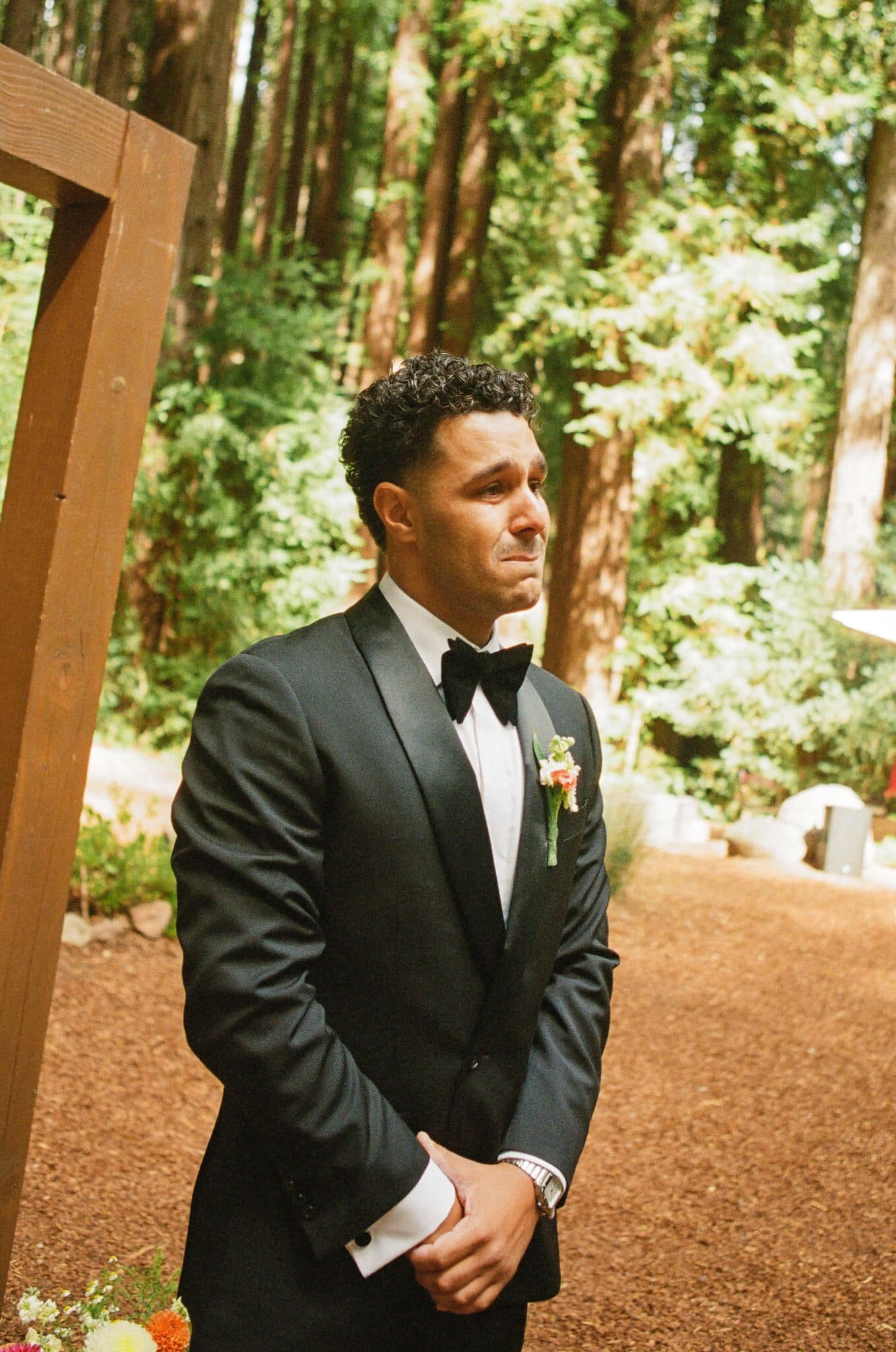 Devin waiting at the ceremony arch among the redwoods, on film