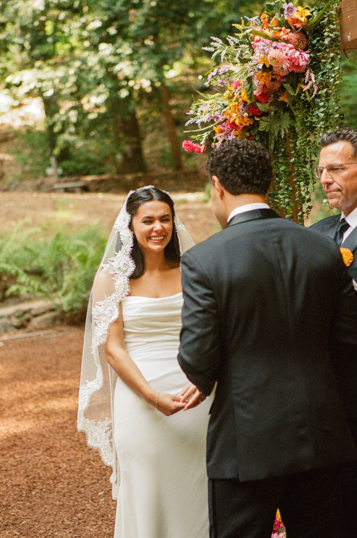 Sofia and Devin meeting at the floral arch during their ceremony, on film