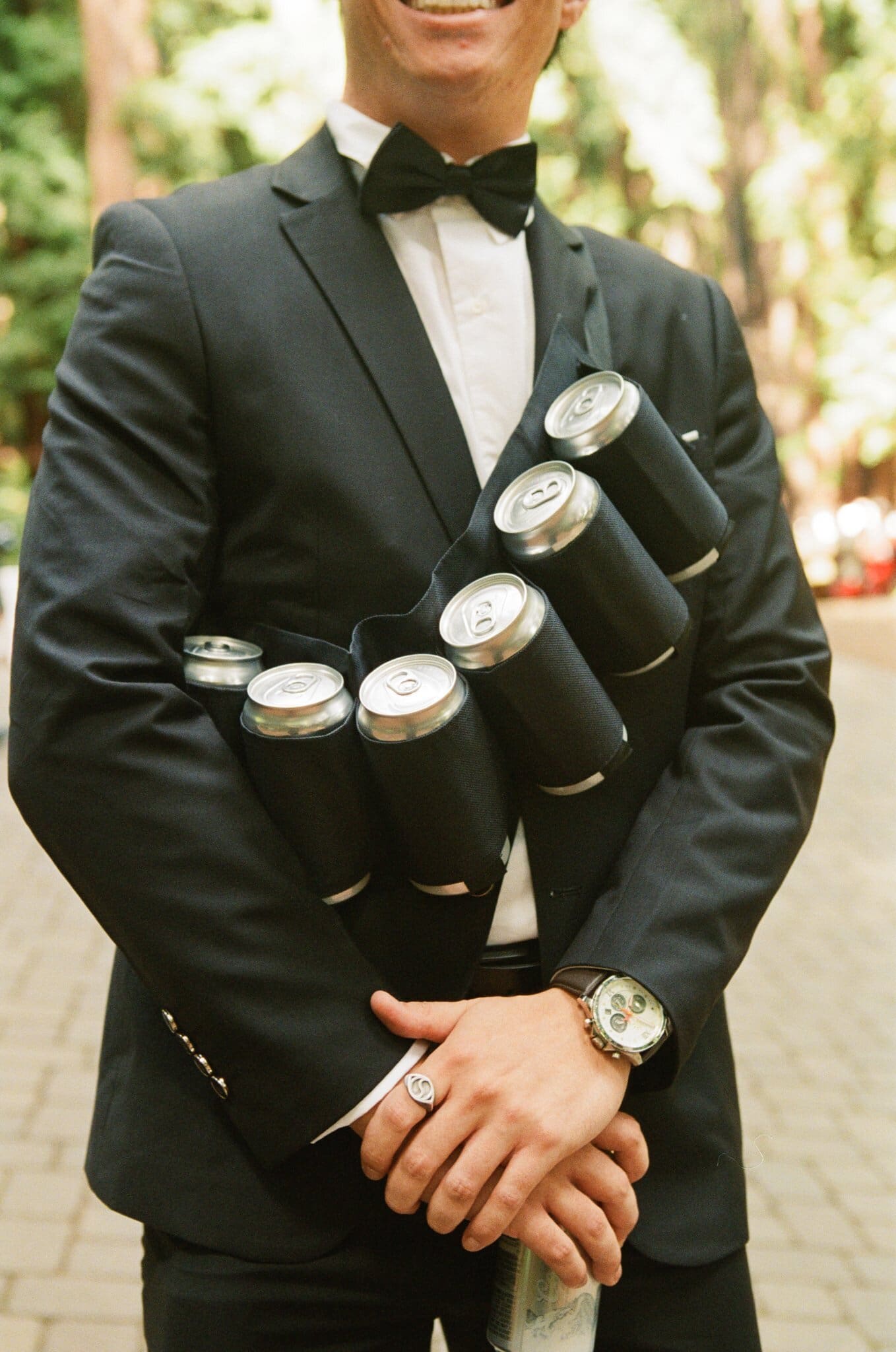 Wedding party member wearing a bandolier of drink cans, on film