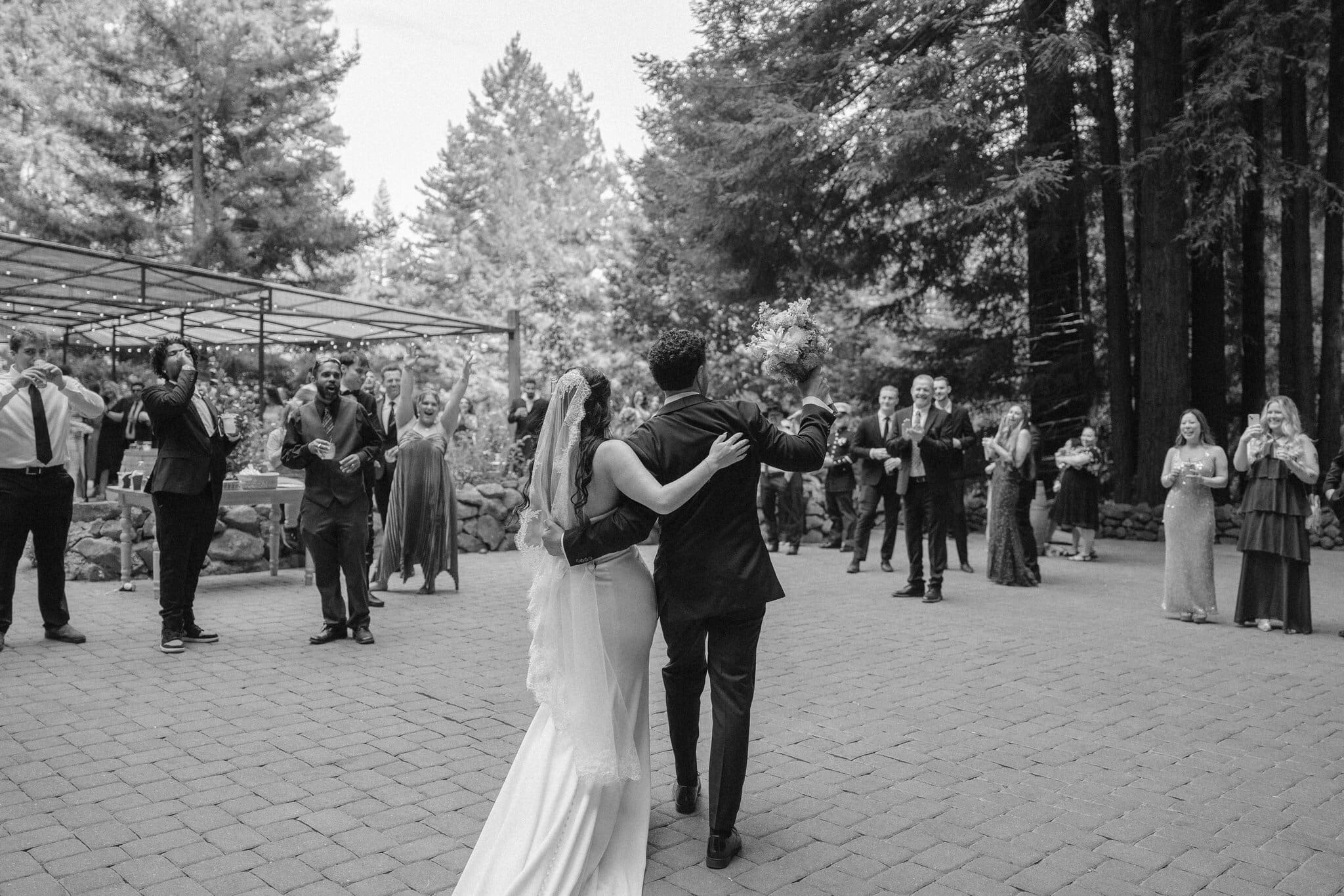 Sofia and Devin walking arm in arm into cocktail hour, black and white