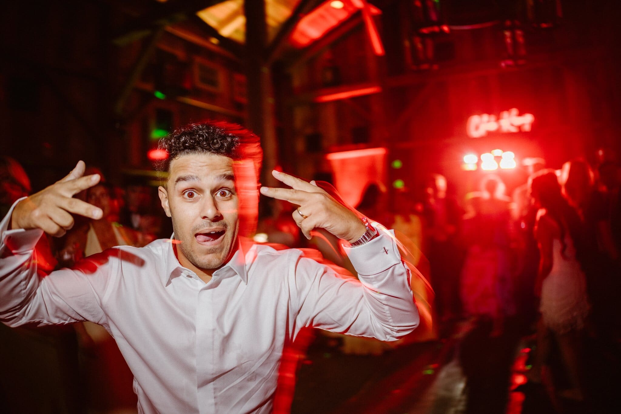 Guest posing under red lights on the dance floor