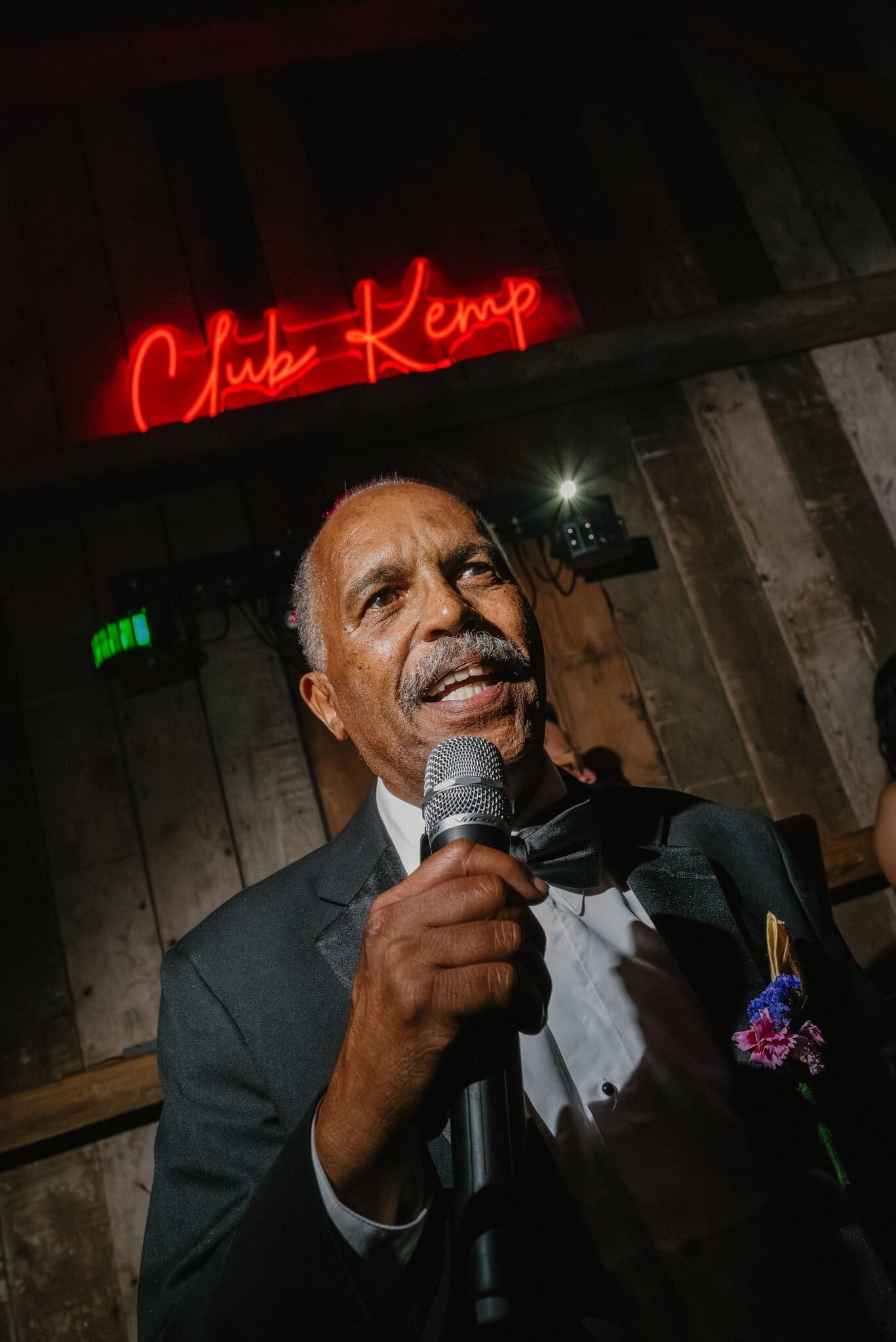 Guest giving a toast under the Club Kemp neon sign