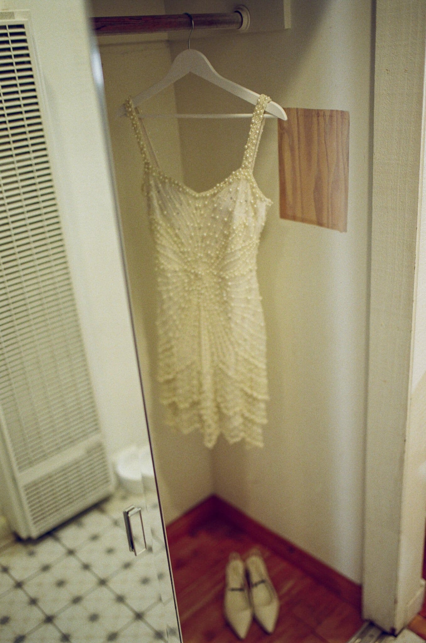 Beaded reception dress and shoes hanging in the bridal suite, on film
