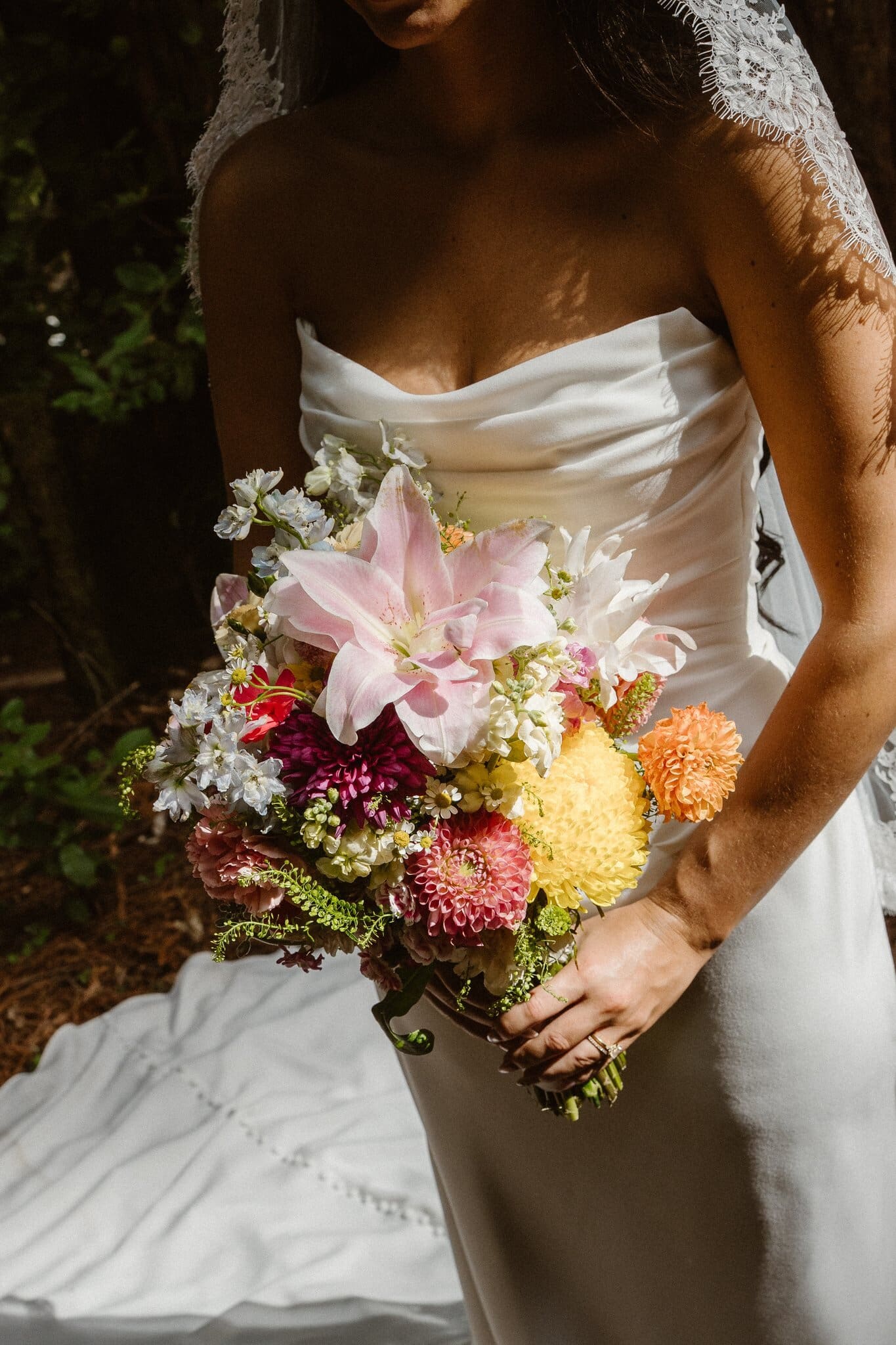 Sofia holding her bouquet in dappled redwood light