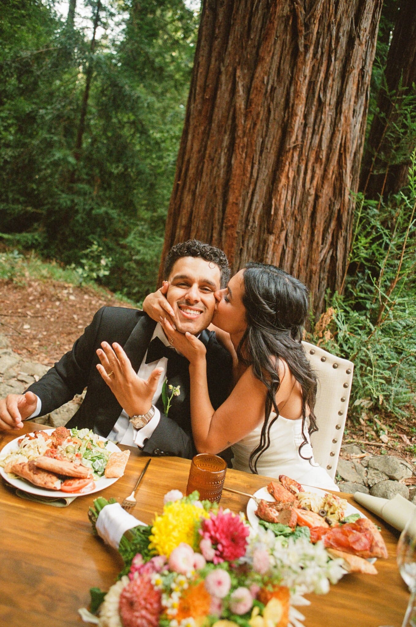 Sofia kissing Devin's cheek at their dinner table, on film