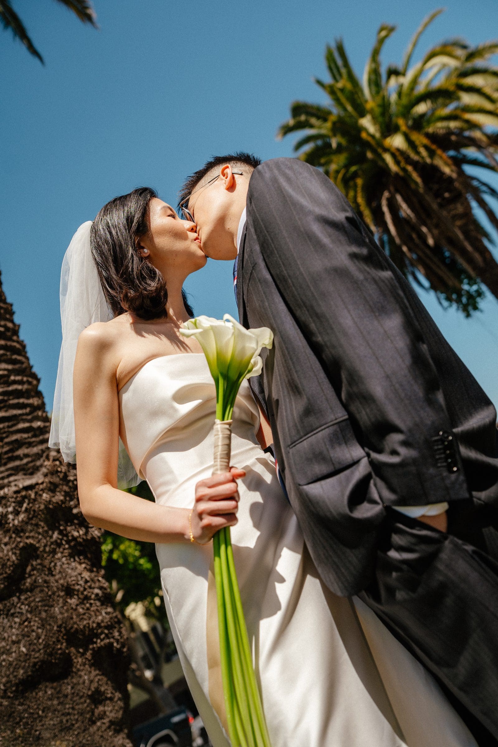 Hsiang and Ting kissing beneath the palm trees in Dolores Park