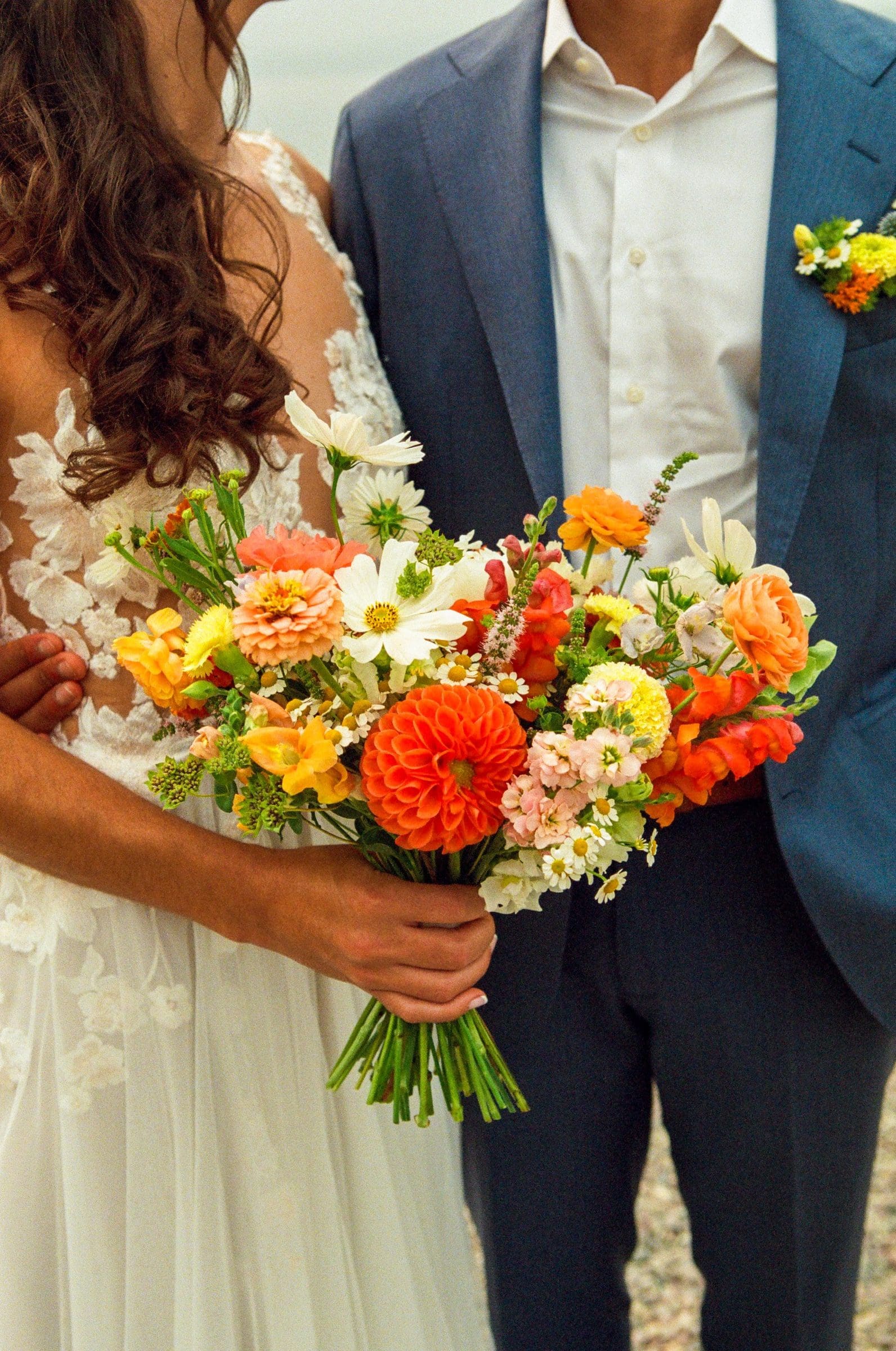 Isabelle's bright orange bouquet held between Raj and Isabelle, on film