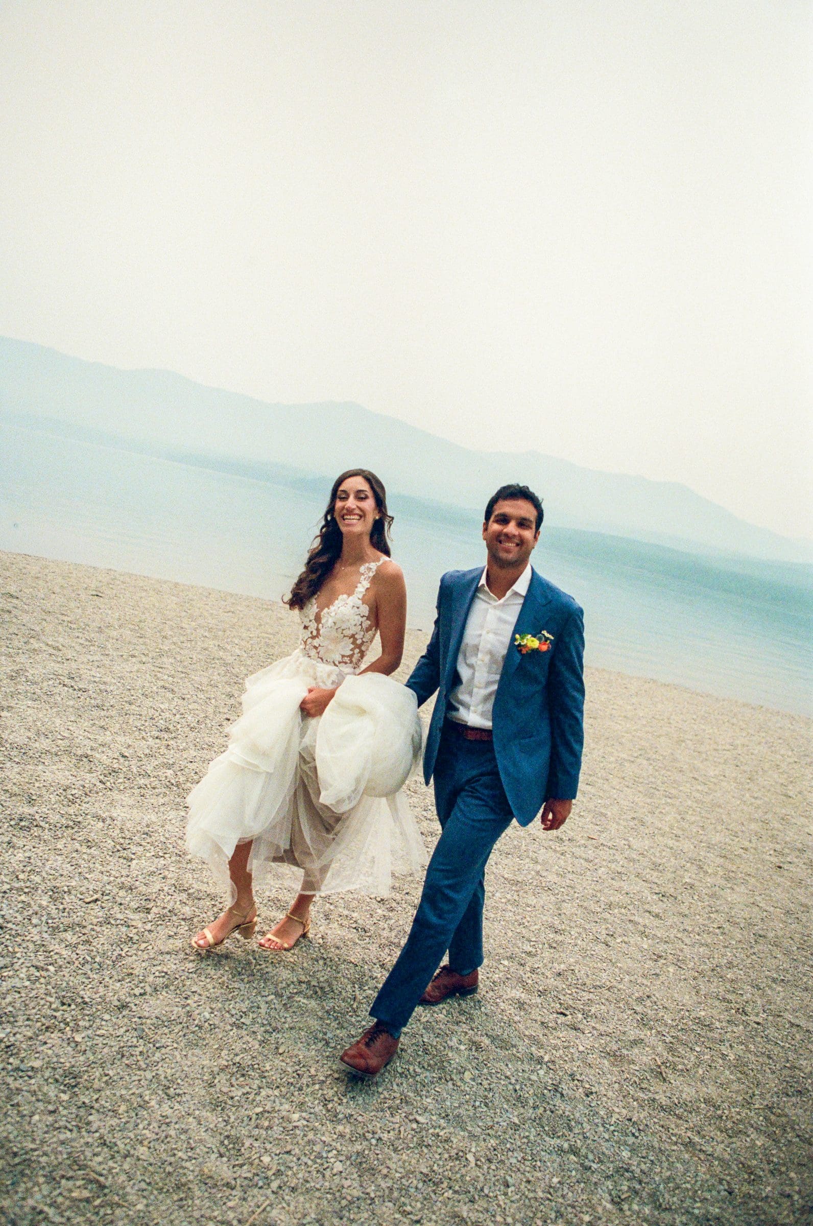 Raj and Isabelle walking along the rocky shore of Lake McDonald, on film