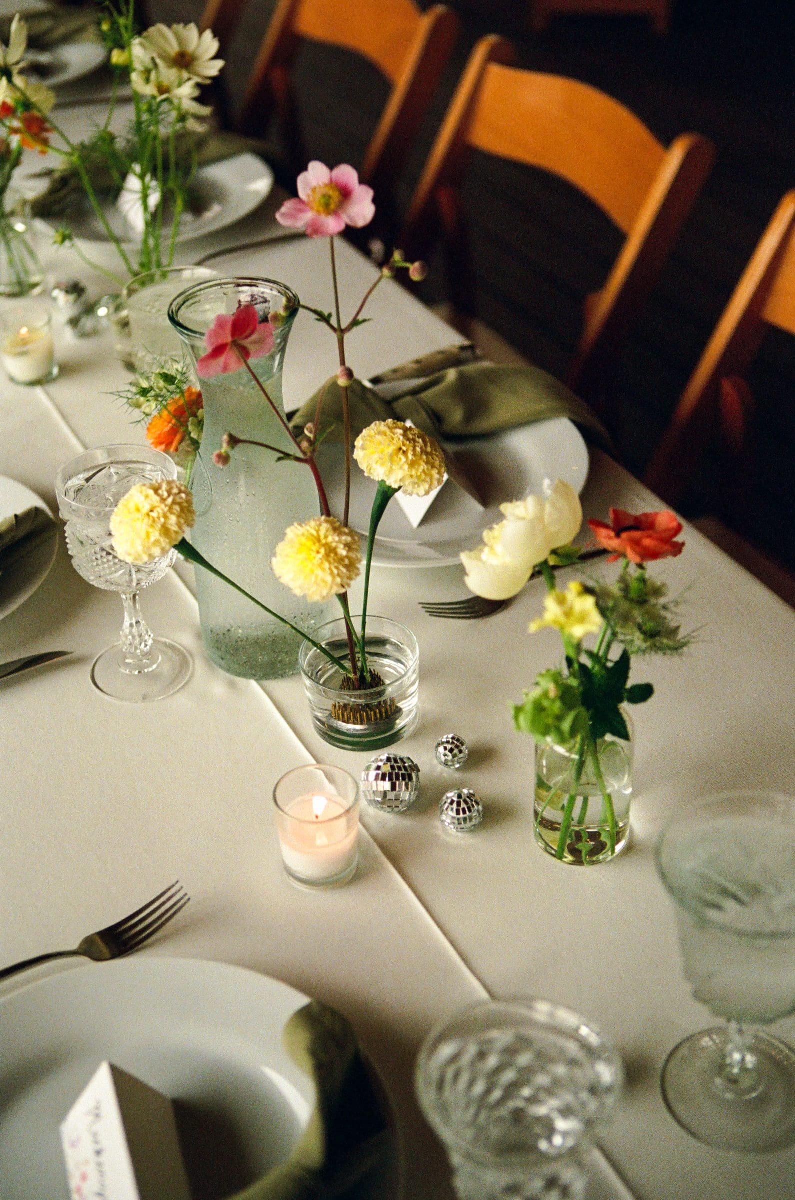 Wildflower bud vases and place settings on a reception table, on film